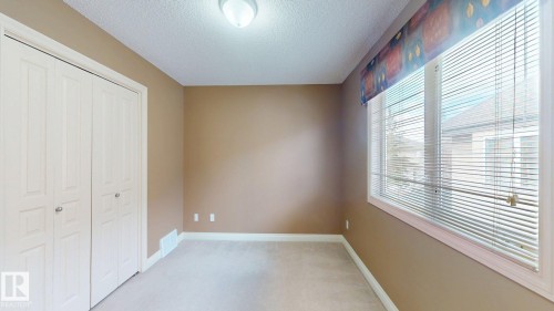 This room features light brown walls, a window with blinds, and white bi-fold closet doors - 613 Todd Link, Edmonton, AB - Indoor Photo Showing Other Room