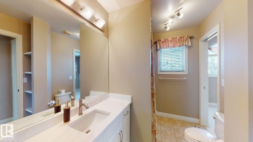 The bathroom features a vanity with a white countertop, an undermount sink, and a large mirror - 613 Todd Link, Edmonton, AB - Indoor Photo Showing Bathroom