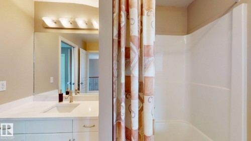 Bathroom featuring a vanity with a white countertop and an integrated sink, a large mirror, and a shower with a white tub - 613 Todd Link, Edmonton, AB - Indoor Photo Showing Bathroom