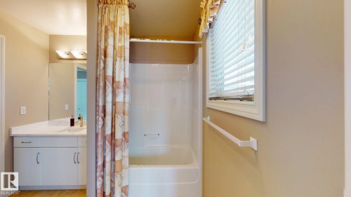 Bathroom featuring a vanity with a white countertop and cabinet, a rectangular mirror, and a shower-tub combination with a window - 613 Todd Link, Edmonton, AB - Indoor Photo Showing Bathroom
