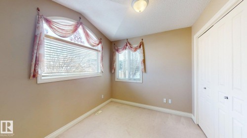 The property features neutral-toned walls, two windows with blinds, and white bi-fold closet doors - 613 Todd Link, Edmonton, AB - Indoor Photo Showing Other Room