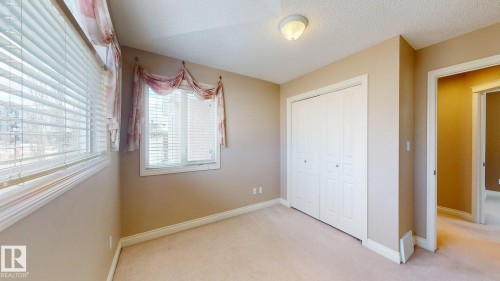 This room features a window with horizontal blinds, a carpeted floor, and a closet with bifold doors - 613 Todd Link, Edmonton, AB - Indoor Photo Showing Other Room