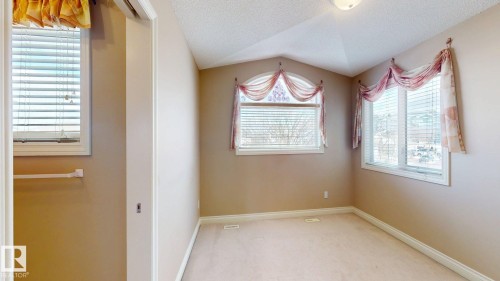 This room features carpeted flooring, two windows with blinds, and a sloped ceiling with a central light fixture - 613 Todd Link, Edmonton, AB - Indoor Photo Showing Other Room
