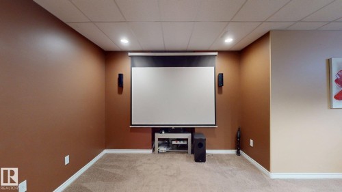This versatile room features warm-toned walls, recessed lighting, and a projection screen with speakers, creating an ideal entertainment space - 613 Todd Link, Edmonton, AB - Indoor Photo Showing Other Room