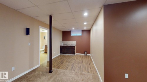 This spacious lower level features both carpeted and wood-look flooring, recessed lighting, and a built-in wet bar with dark cabinetry and a light-colored countertop - 613 Todd Link, Edmonton, AB - Indoor