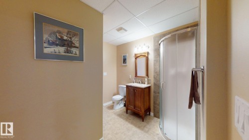 Bathroom featuring a curved glass shower enclosure, a wooden vanity with a white countertop and double faucets, and a toilet - 613 Todd Link, Edmonton, AB - Indoor