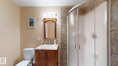This bathroom features a wood vanity with a marble countertop and an integrated sink, illuminated by a vanity light fixture - 613 Todd Link, Edmonton, AB - Indoor Photo Showing Bathroom
