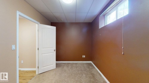 This room features neutral-toned carpet flooring, a window providing natural light, and a white interior door - 613 Todd Link, Edmonton, AB - Indoor Photo Showing Other Room