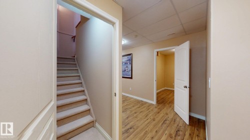The property features a staircase with carpeted treads and a landing, alongside a hallway with wood-look flooring - 613 Todd Link, Edmonton, AB - Indoor Photo Showing Other Room