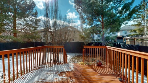 The property features a spacious wooden deck with a railing, overlooking a yard with a lawn and mature trees - 613 Todd Link, Edmonton, AB - Outdoor With Deck Patio Veranda