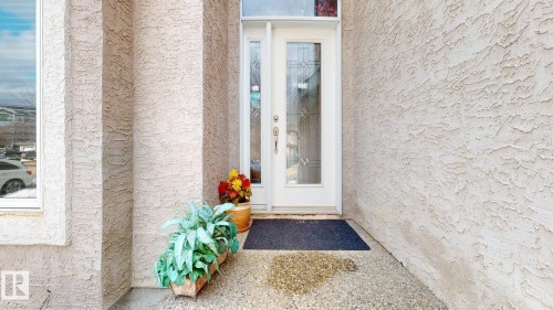 The property features an exterior with textured stucco walls, a white front door with decorative glass inserts, and a transom window above the door - 613 Todd Link, Edmonton, AB - Outdoor