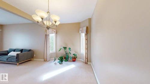 Living area featuring a chandelier, two windows with valances, and light-colored carpeting - 613 Todd Link, Edmonton, AB - Indoor Photo Showing Other Room