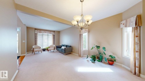 Spacious room featuring light-colored carpeting, multiple windows providing natural light, and a ceiling-mounted light fixture - 613 Todd Link, Edmonton, AB - Indoor