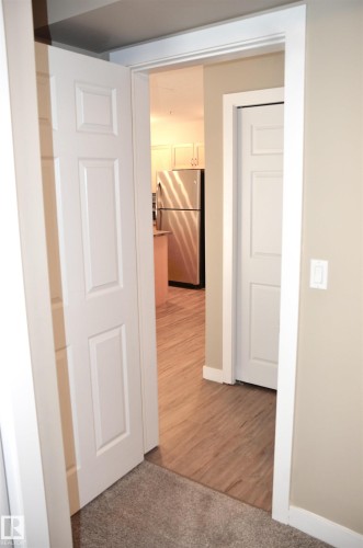 Transition from carpeted hallway to wood-finish flooring - 103 920 156 Street Nw, Edmonton, AB - Indoor Photo Showing Other Room