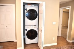 Dedicated laundry closet featuring a stacked washer and dryer, wood-finish flooring, and neutral wall paint - 