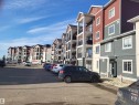 Multi-story residential complex featuring red and gray siding, white trim, and individual balconies with black railings - 103 920 156 Street Nw, Edmonton, AB  - Outdoor With Facade 