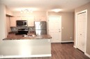 Open-concept kitchen featuring stainless steel appliances, wood-finish cabinetry, a breakfast bar, and wood-finish flooring - 103 920 156 Street Nw, Edmonton, AB  - Indoor Photo Showing Kitchen 