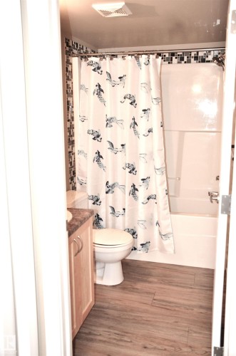 Bathroom featuring a white bathtub, toilet, and wood-finish vanity with a countertop - 103 920 156 Street Nw, Edmonton, AB - Indoor Photo Showing Bathroom