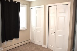Interior room featuring two paneled bi-fold closet doors, a single window with white trim, and light brown carpeting - 