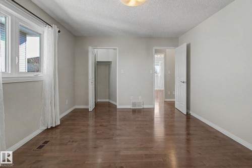 Spacious room featuring wood-finish flooring, white trim, and light-toned walls - 3903 32 Street, Edmonton, AB - Indoor Photo Showing Other Room