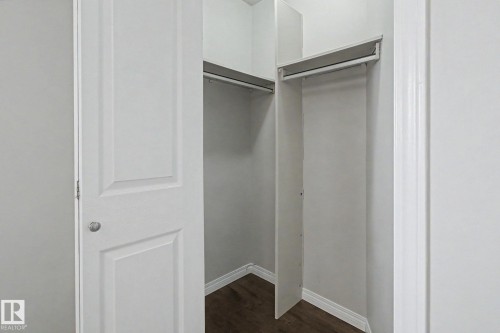 Walk-in closet featuring wood-finish flooring, white baseboards, and built-in shelving with hanging rods - 3903 32 Street, Edmonton, AB - Indoor Photo Showing Other Room