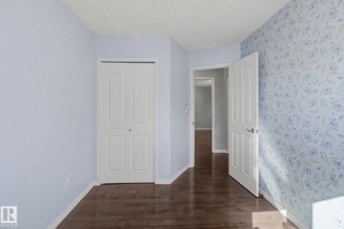 Wood-finish flooring throughout, complemented by light blue painted walls and patterned wallpaper - 3903 32 Street, Edmonton, AB - Indoor