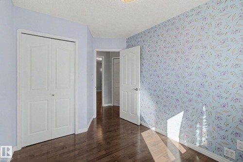 Room with wood-finish flooring, light blue walls, and one accent wall featuring floral wallpaper - 3903 32 Street, Edmonton, AB - Indoor