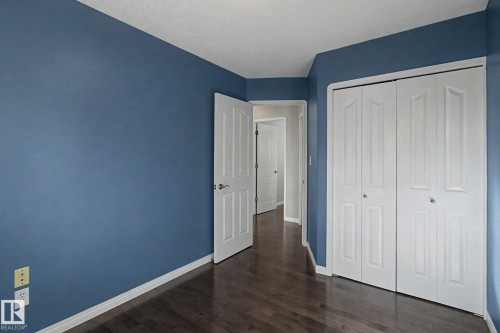 Interior room with deep blue walls, dark wood-finish flooring, and white trim - 3903 32 Street, Edmonton, AB - Indoor