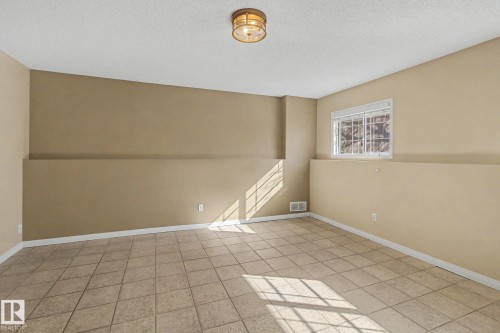 Spacious room featuring neutral-toned walls, a white ceiling, and light-colored tile flooring - 3903 32 Street, Edmonton, AB - Indoor Photo Showing Other Room