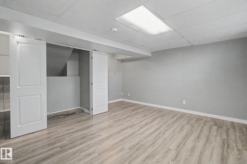 Spacious room with wood-finish flooring and neutral gray walls - 3903 32 Street, Edmonton, AB - Indoor