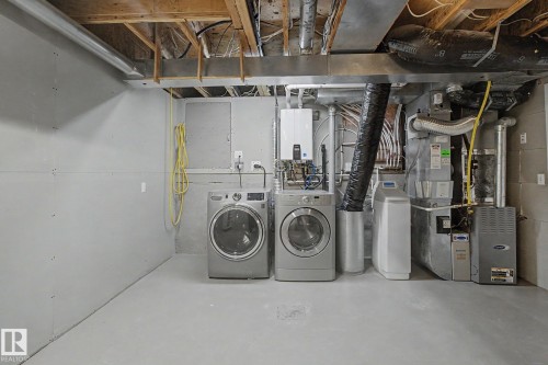 Dedicated utility area featuring washer and dryer appliances, tankless water heater, water softener system, and furnace - 3903 32 Street, Edmonton, AB - Indoor Photo Showing Laundry Room