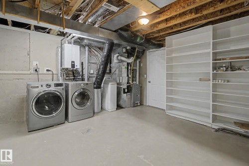 Dedicated utility area featuring a wall-mounted water heater, exposed overhead ductwork, and built-in shelving - 3903 32 Street, Edmonton, AB - Indoor Photo Showing Laundry Room