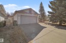 Attached garage with a wide concrete driveway, featuring white siding, a single garage door, and an exterior light fixture - 3903 32 Street, Edmonton, AB  - Outdoor 