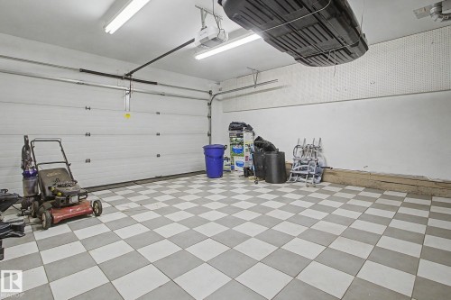 Spacious garage featuring a sectional garage door, checkerboard floor tiling, overhead fluorescent lighting, and a garage door opener - 3903 32 Street, Edmonton, AB - Indoor Photo Showing Garage