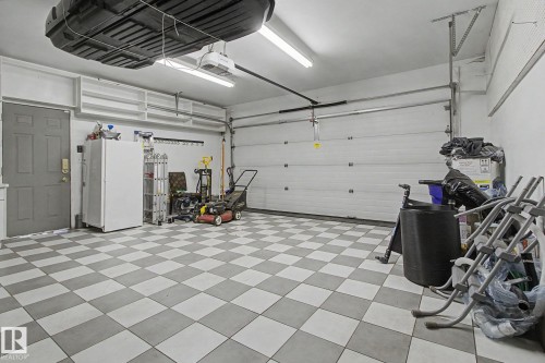 Garage featuring checkerboard floor tiles, built-in overhead storage shelves, a pedestrian door, and an automatic garage door opener - 3903 32 Street, Edmonton, AB - Indoor Photo Showing Garage