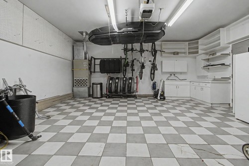 Garage featuring checkerboard pattern flooring, extensive built-in cabinetry, wall-mounted shelving, and overhead fluorescent lighting - 3903 32 Street, Edmonton, AB - Indoor