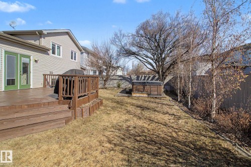 Expansive backyard featuring a multi-level wood deck with railing, providing direct access to the interior via green-framed French doors - 3903 32 Street, Edmonton, AB - Outdoor
