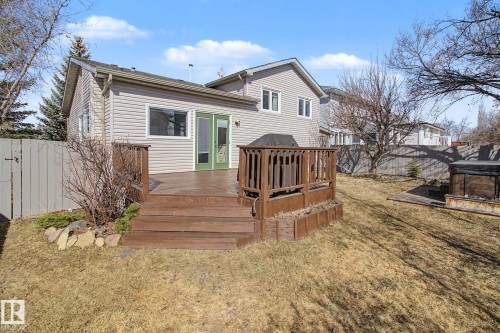 Rear exterior featuring a multi-level wood deck with stairs, light-colored horizontal siding, and green patio doors - 3903 32 Street, Edmonton, AB - Outdoor