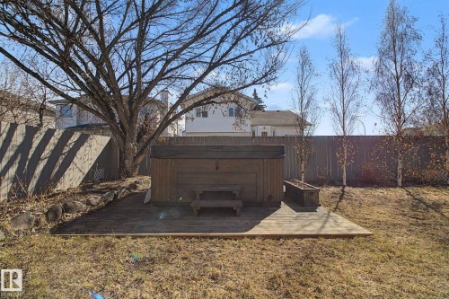 Backyard featuring a built-in outdoor spa on a wood-finish deck, surrounded by a privacy fence and mature trees - 3903 32 Street, Edmonton, AB - Outdoor