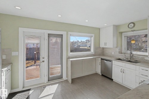 Modern kitchen featuring white cabinetry, light-toned countertops, tile backsplash, and stainless steel appliances - 3903 32 Street, Edmonton, AB - Indoor Photo Showing Kitchen With Double Sink