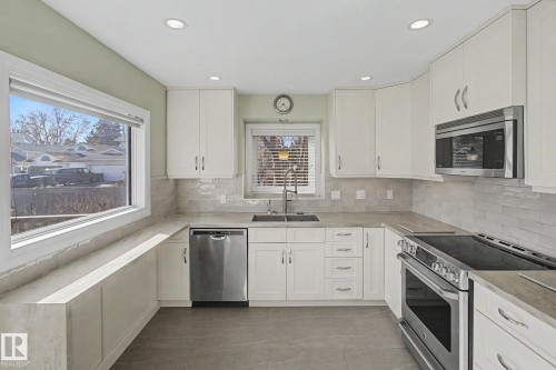 Modern kitchen featuring white cabinetry, stainless steel appliances, light-toned countertops, a subway tile backsplash, and recessed lighting - 3903 32 Street, Edmonton, AB - Indoor Photo Showing Kitchen With Upgraded Kitchen