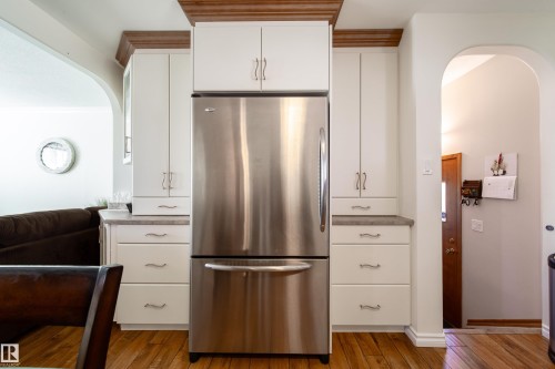 Stainless steel refrigerator framed by white cabinetry with wood-finish crown molding - 8932 154 Street, Edmonton, AB - Indoor Photo Showing Kitchen
