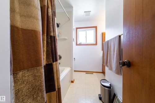 Bathroom featuring a white bathtub, a window with wood trim, and light-toned flooring - 8932 154 Street, Edmonton, AB - Indoor