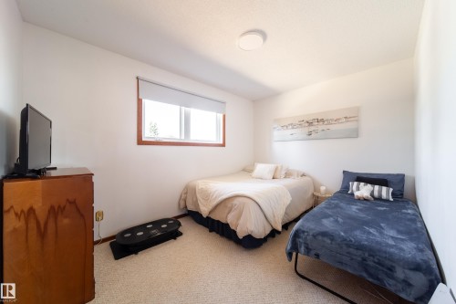 Neutral white walls with a single window featuring wood-finish trim and a roller shade - 8932 154 Street, Edmonton, AB - Indoor Photo Showing Bedroom