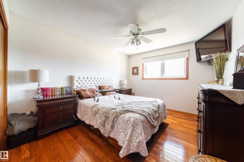 Spacious room featuring wood-finish flooring, a ceiling fan, and a large window with wood trim - 8932 154 Street, Edmonton, AB - Indoor Photo Showing Bedroom
