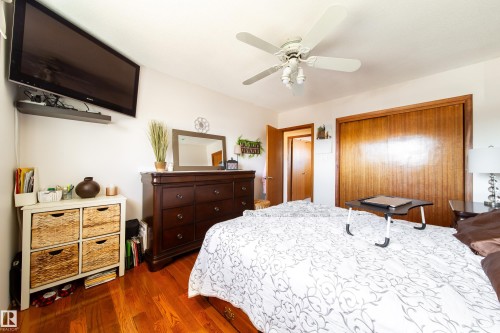 Bedroom featuring wood-finish flooring, a ceiling fan with integrated lighting, and a built-in closet with wood sliding doors - 8932 154 Street, Edmonton, AB - Indoor Photo Showing Bedroom