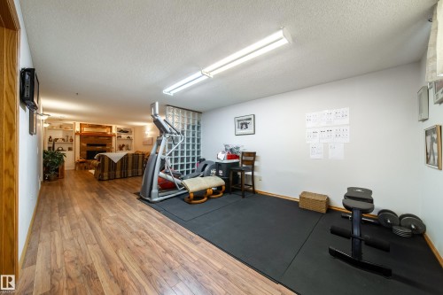 Spacious room featuring wood-finish flooring, a glass block partition, recessed lighting, and a white ceiling - 8932 154 Street, Edmonton, AB - Indoor