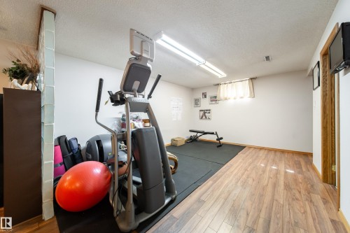 Versatile room featuring wood-finish flooring and a section of black mat flooring - 8932 154 Street, Edmonton, AB - Indoor Photo Showing Gym Room