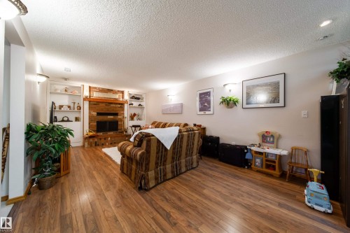 Spacious room featuring wood-finish flooring, a brick fireplace with a wood mantle, and built-in shelving on either side - 8932 154 Street, Edmonton, AB - Indoor Photo Showing Living Room With Fireplace