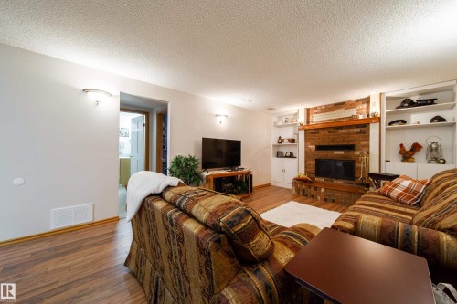 Living area featuring a brick fireplace with a wood mantle - 8932 154 Street, Edmonton, AB - Indoor Photo Showing Living Room With Fireplace